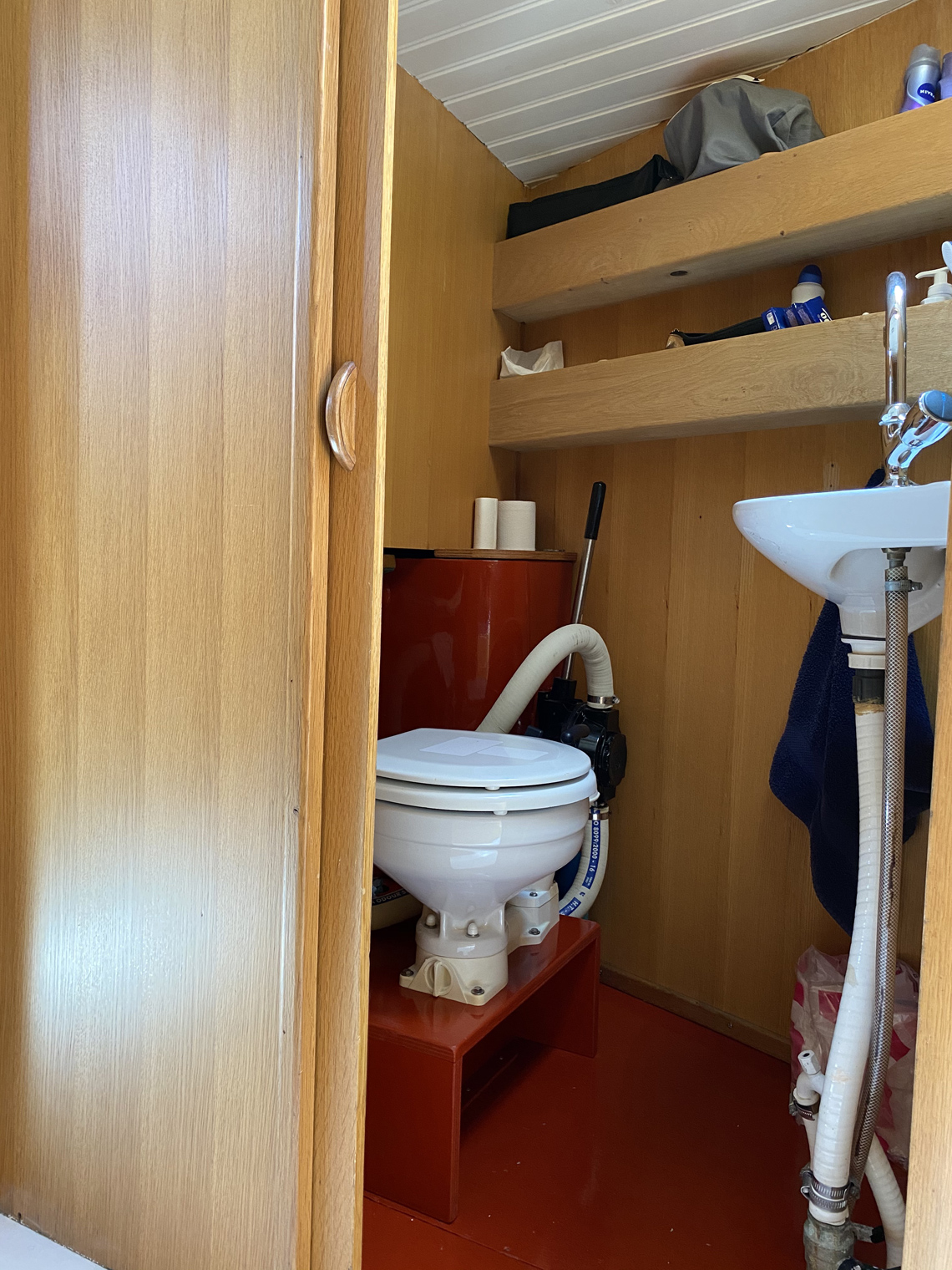 Toilet met schuifdeur. Vuilwatertank en wastafel met spiegel.